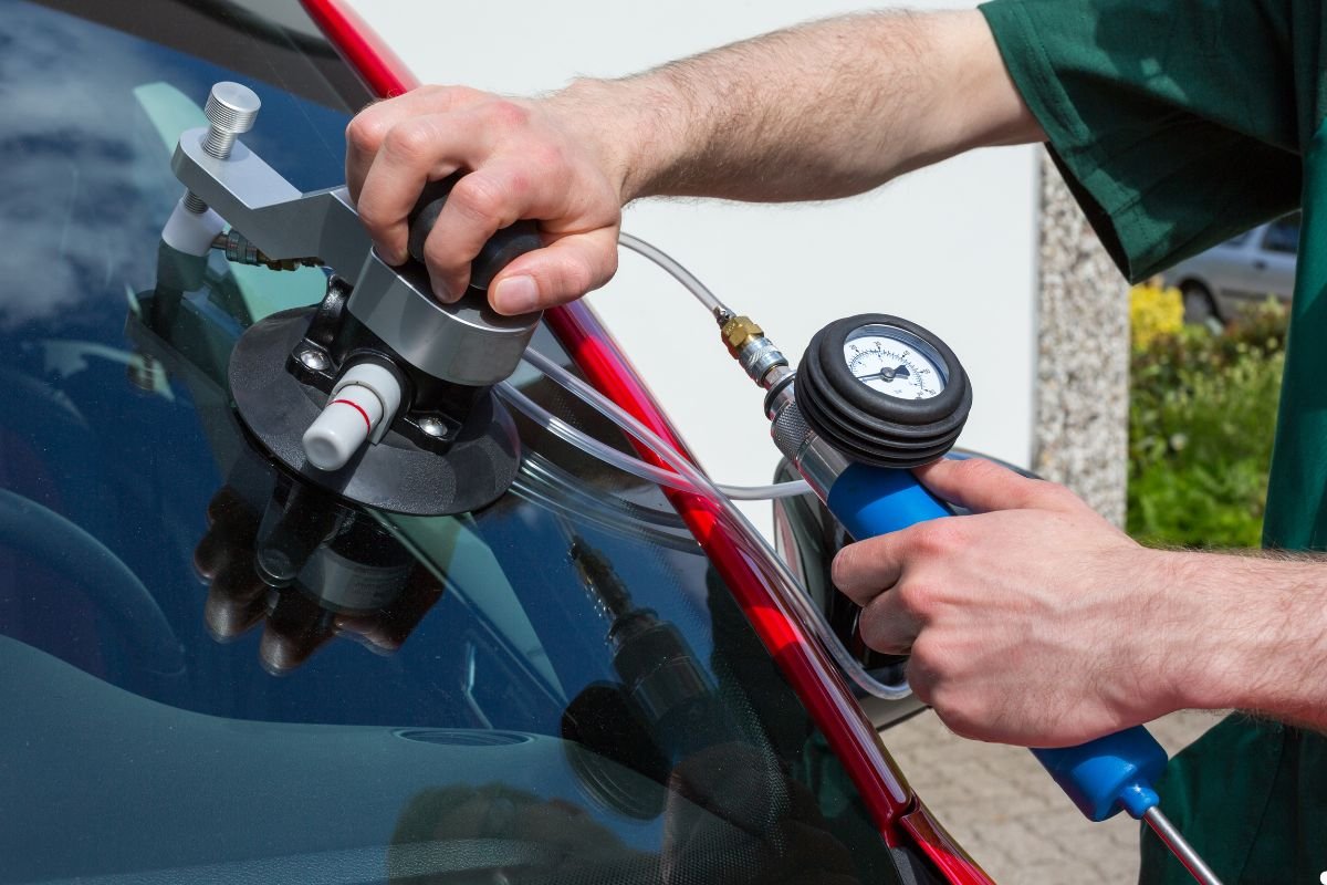 A man cleans a car window with a glass cleaner, focusing on removing streaks for a clear view.